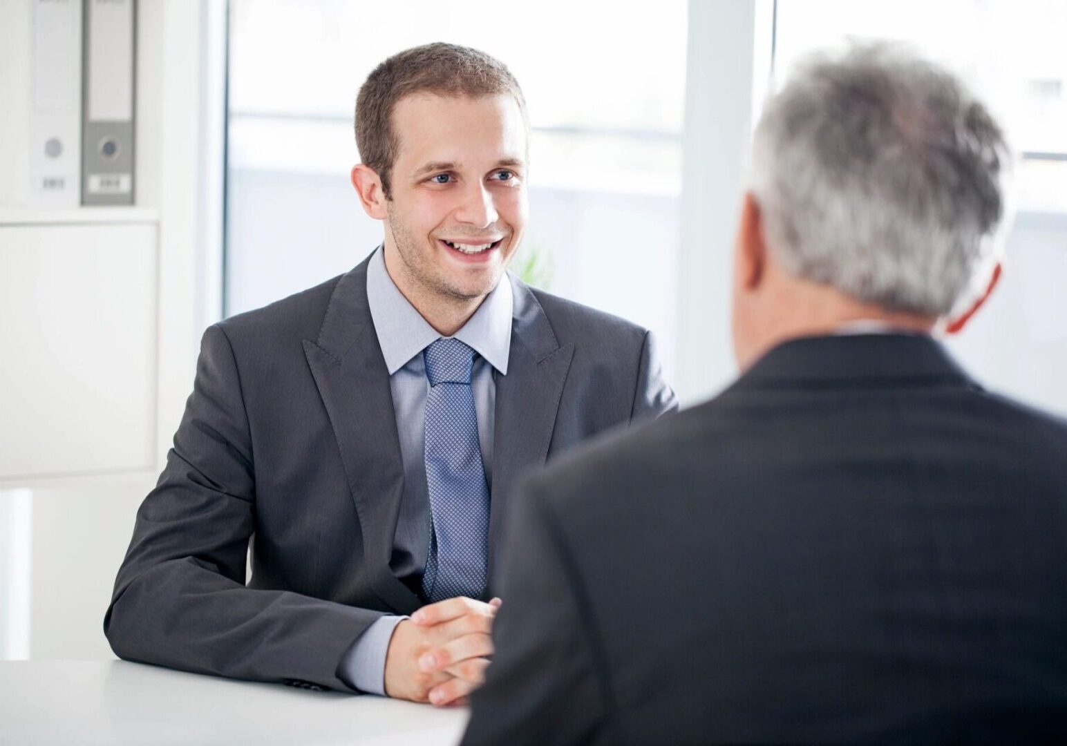 A man in suit and tie shaking hands with another person.