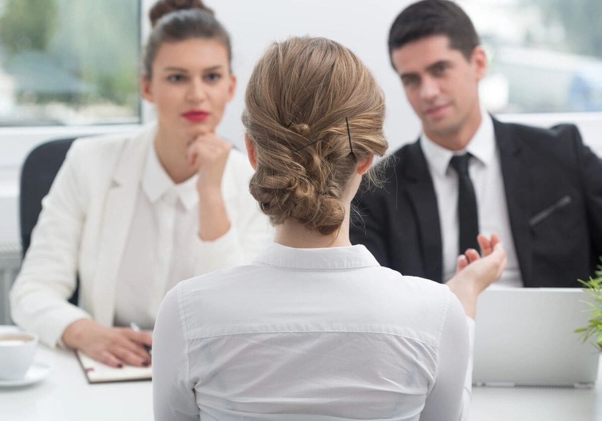 A woman is sitting in front of two men.